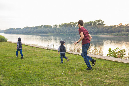 家庭预算表摄影照片_童年、家庭观念 — 父亲在湖边和两个儿子玩耍