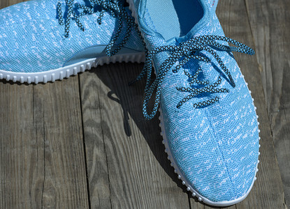 一双鞋运动鞋摄影照片_灰色木质表面上的一双蓝色纺织鞋