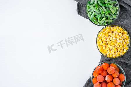 三碗黄色玉米、青豆、红色西红柿的冷冻蔬菜食品。