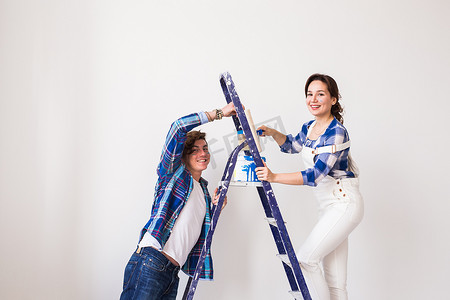 家庭、装修、幸福和重新装修的概念 — 年轻家庭一起修理、一起粉刷墙壁、大笑