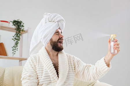 皮肤喷雾摄影照片_留着胡须的男性头上戴着浴巾，在脸上喷水处理。