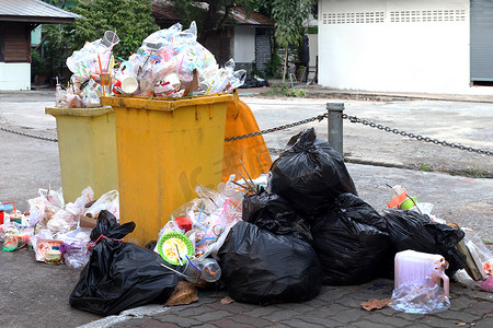 人行道上成堆的垃圾塑料黑和垃圾袋垃圾，污染垃圾，地板上的塑料垃圾和塑料袋泡沫托盘垃圾，废塑料是走在路上的背景人