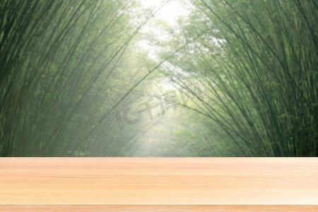 空木桌地板在模糊的竹绿色软背景上，木桌板空前拱形竹树模糊自然，竹树上的木板坯用于模拟展示产品