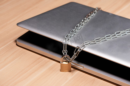 桌上笔记本电脑周围挂着挂锁的重链。