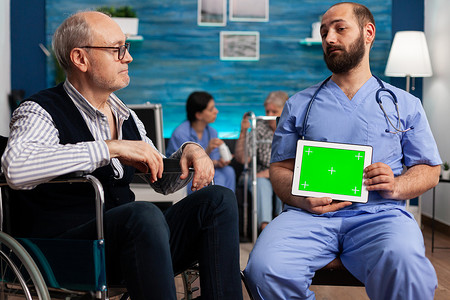 助理护理人员拿着带隔离显示器的模拟绿屏色度键平板电脑
