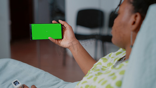 绿屏手机屏幕摄影照片_拿着有水平的绿色屏幕的智能手机的病的患者