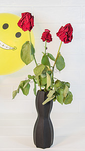 老玫瑰背景上的微笑气球。三朵枯萎的玫瑰