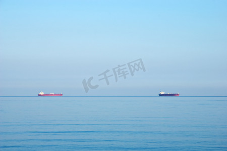 油轮摄影照片_阴云密布的天空下地平线上的油轮货船