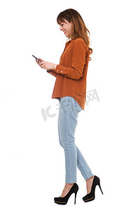 年轻女子在孤立的白色背景下走路和看手机的侧面肖像