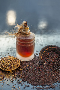 生有机草药香料芥末籽或 sarso 或 rai 或黑芸苔，在木质表面的粘土碗中，其提取的精油在透明玻璃瓶中。