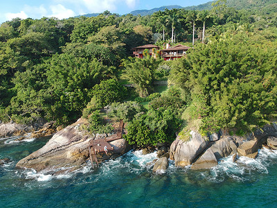 热带森林中的豪华房屋，四周环绕着树木，毗邻大海和碧绿的海水