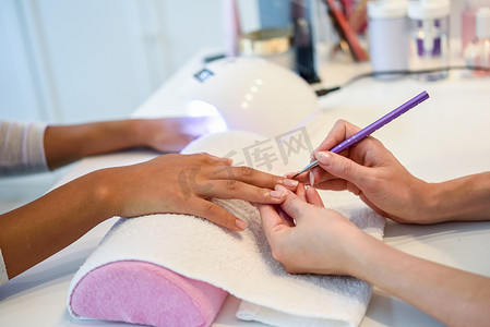 美容师在美甲沙龙用刷子给女人涂指甲的特写