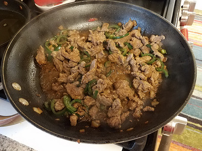 炉子上煎锅里的牛肉和青椒
