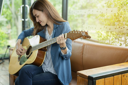 弹窗摄影照片_美丽的女孩在窗边弹吉他。