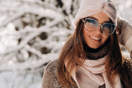 冬天，一个穿着毛衣和眼镜的女孩在白雪覆盖的森林里