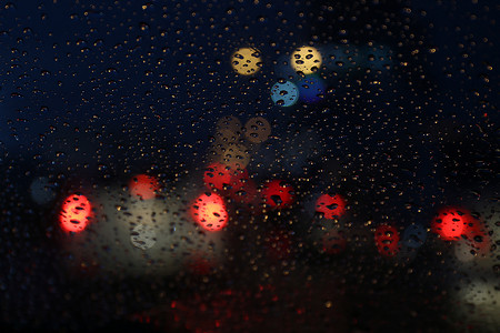 夜生活背景散景和玻璃上的雨滴模糊散景照明五颜六色的凝结