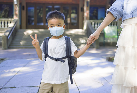 孩子舞龙摄影照片_在冠状病毒或流感爆发期间，母亲和孩子戴着口罩上学。