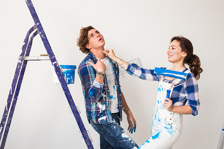 粉刷滚筒摄影照片_修复、翻新和爱情情侣概念 — 年轻的家庭一起做重新装修和粉刷墙壁，一起笑。