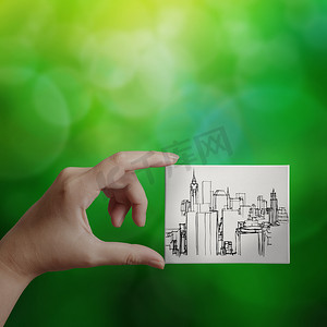 手在画布板上显示手绘城市在绿色自然 bac