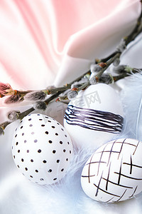 时髦的彩色时尚天然复活节彩蛋、羽毛、白色丝绸质朴布上的褪色柳枝。