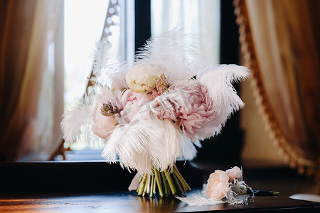 新娘的婚礼玫瑰花束，上面装饰着白色的羽毛和胸花