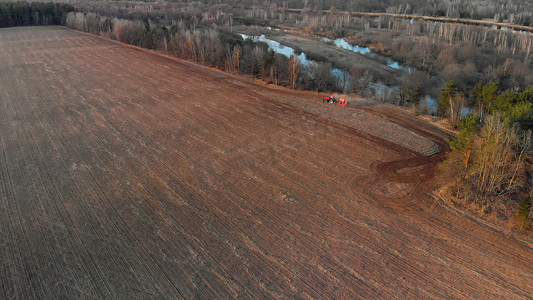 保护耕地摄影照片_空中：拖拉机在河边耕种农田。