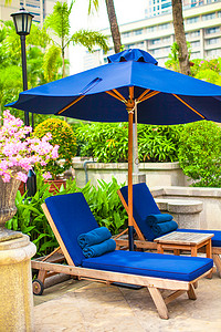 豪华酒店游泳池附近两张带遮阳伞的蓝色躺椅