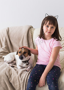 沙发上的狗狗摄影照片_可爱的小狗杰克罗素梗在沙发上的小女孩。
