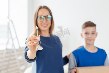 乔迁大特惠摄影照片_乔迁后，模模糊糊的漂亮妈妈和儿子拿着新公寓的钥匙。
