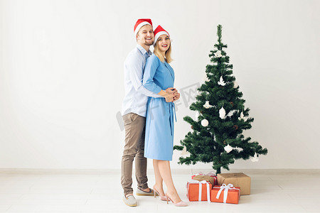 寒假展架摄影照片_寒假和家庭观念 — 快乐的年轻夫妇在家附近的圣诞树