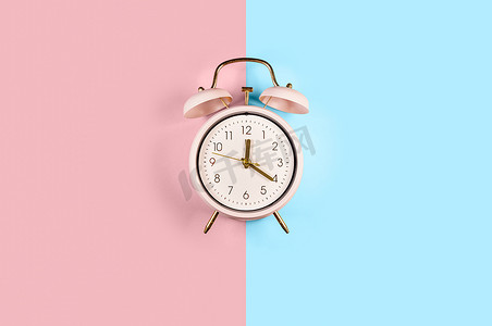 蓝色和粉红色柔和色彩时尚背景中突显的双铃复古经典闹钟
