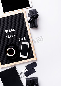 黑色背景宣传摄影照片_在黑色字母板上发短信黑色星期五销售，上面有咖啡、智能手机、白色背景上的价格标签