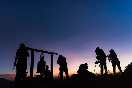 悬崖上的摄影师剪影反对多彩的黄昏天空
