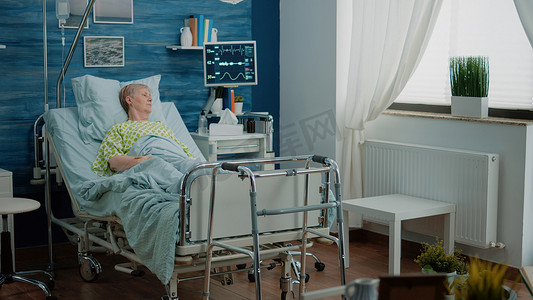 养老院设施摄影照片_生病的老妇人躺在疗养院的病床上