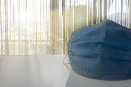 防尘口罩摄影照片_带有阳光背景的桌子上的医用防护面具。