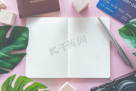 削笔刀包装摄影照片_空白空间白色笔记本和笔的顶部视图，带有护照、相机、信用卡和墙壁等旅行装备作为图片框架。