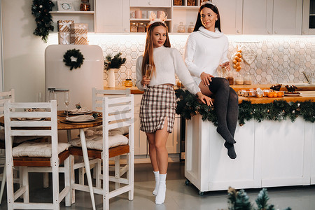 两个女孩在厨房里舒适的家庭环境中，手里拿着香槟过圣诞节。