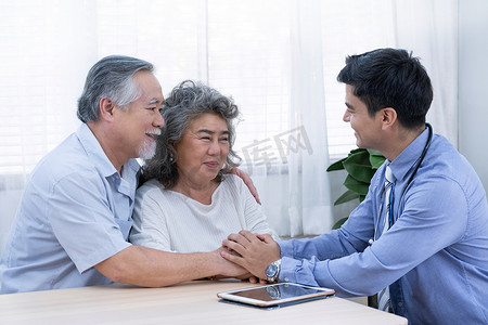 穿蓝色衬衫和听诊器的医生握着他们的手鼓励老人