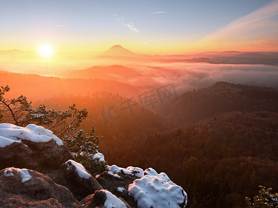 雪顶摄影照片_冻结秋天的黎明，岩石上覆盖着新鲜的粉雪。
