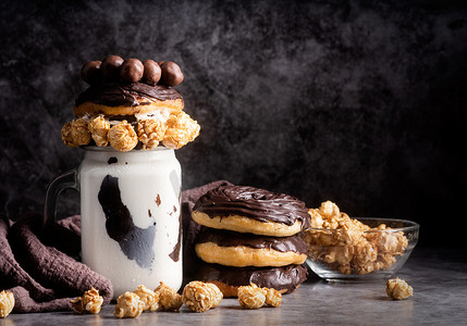 糖果罐摄影照片_用爆米花、生奶油和糖果装饰的巧克力甜甜圈奶昔