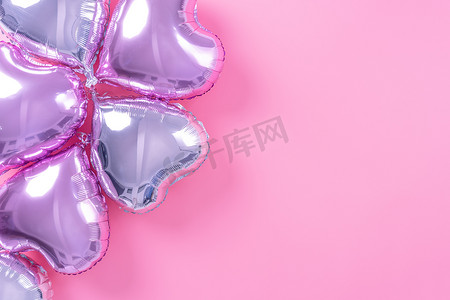 淡粉色摄影照片_情人节最小设计概念 — 美丽的真心形箔气球隔离在淡粉色背景、顶视图、平躺、摄影上方。
