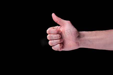 手势很棒的标志摄影照片_欧洲人的手显示拇指信号，通常被描述为孤立黑色背景上的竖起大拇指的标志