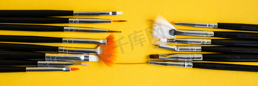 黄色背景上用于指甲设计的黑色刷子，用于在指甲上绘画的美甲工具刷，复制空间，顶视图