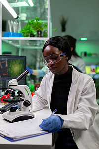 非洲裔美国植物学家研究员在剪贴板上写生物实验结果
