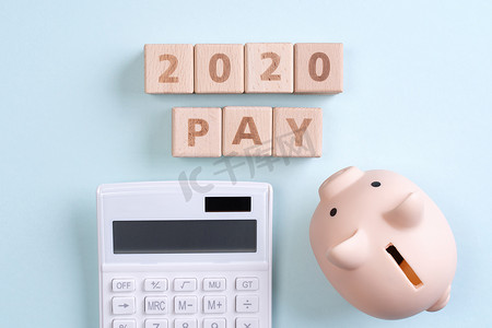 钱几何摄影照片_摘要 2020 年财务目标设计概念 — 蓝桌背景上的几何木块立方体，带有存钱罐、顶视图、平躺、复制空间。