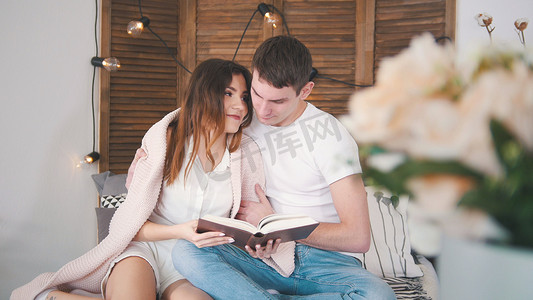 年轻男女在家放松 — 在沙发上看书，互相亲吻快乐