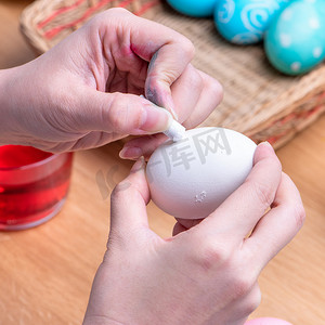 复活节彩蛋准备 — 年轻女性正在用柔和的蜡笔画白蛋，然后在家餐桌上染色，特写，生活方式
