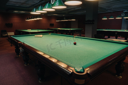 台球游戏摄影照片_台球俱乐部里有绿色表面和球的台球桌。台球比赛