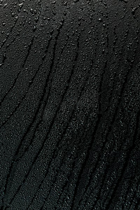 带污迹的黑色平面橡胶表面宏观背景上的水滴