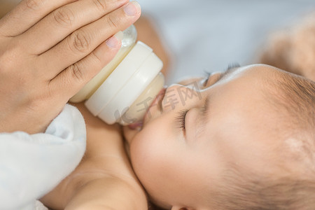 母亲从瓶子里喂奶和婴儿睡觉的手